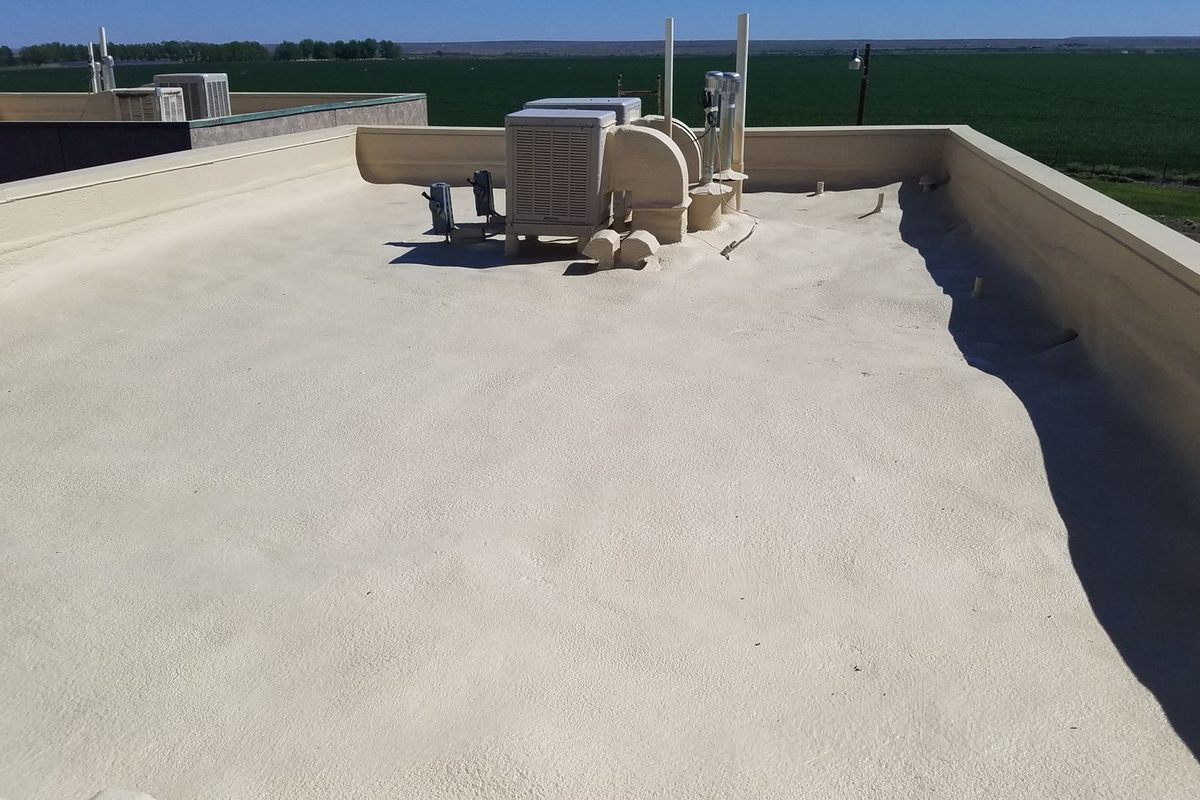 Recoated spray foam roof at the Pecos Apartments in Dexter with the rooftop cooler foamed at its base