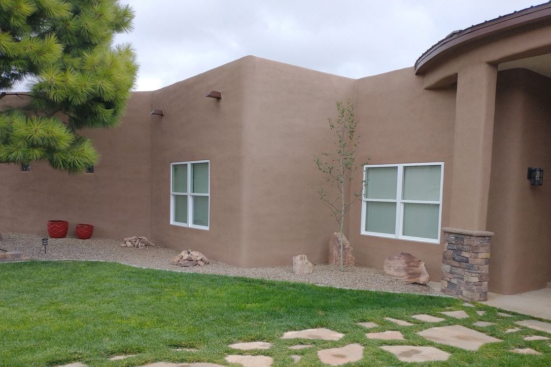 Stucco home with new white windows and the wall finish restored around them