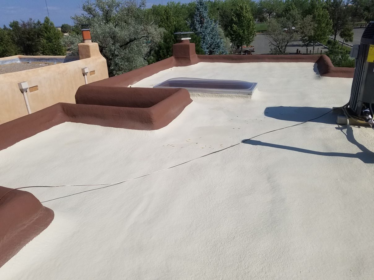 Finished spray foam roof on a Santa Fe adobe home with coated parapet walls and canales