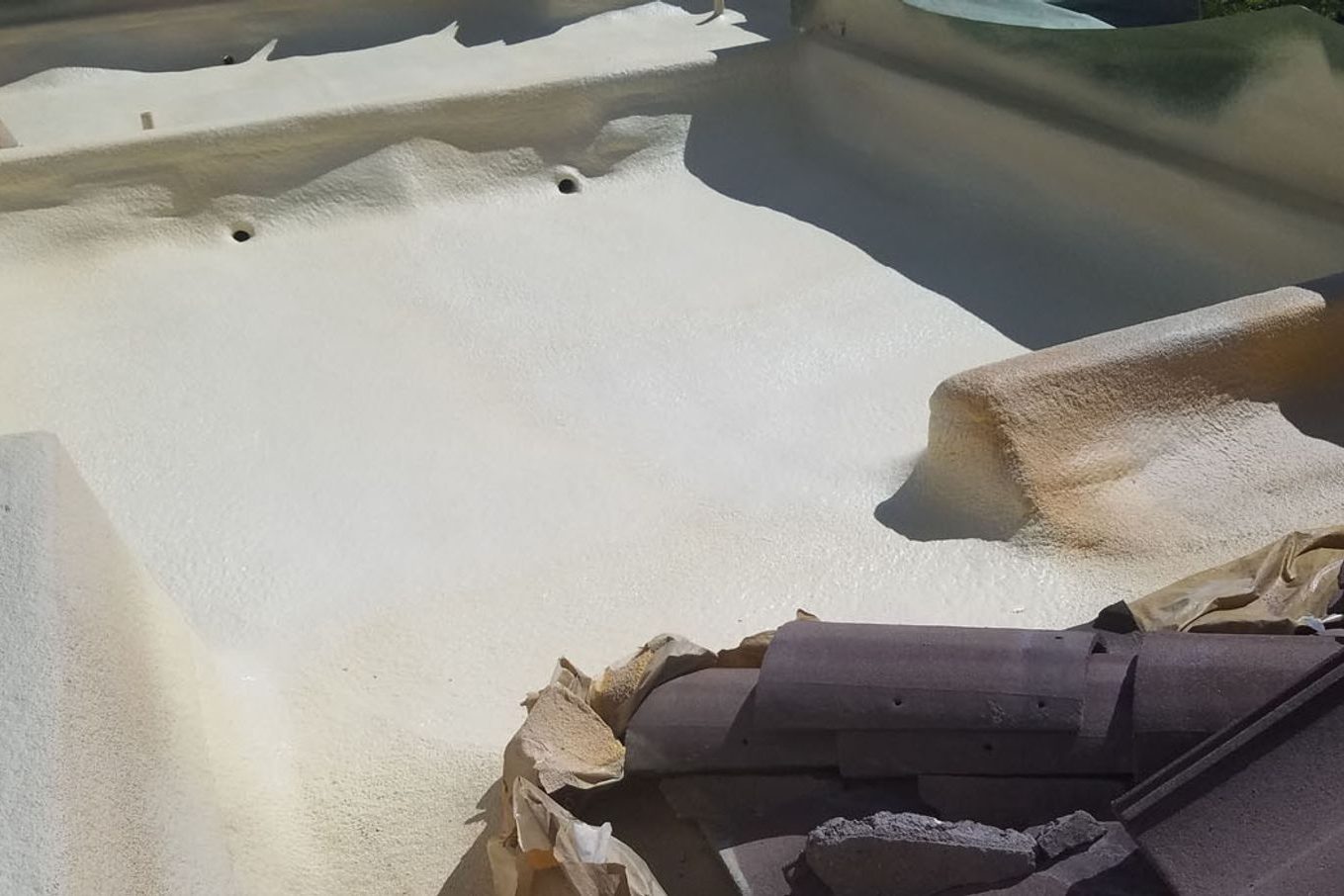 Sprayed polyurethane foam applied to a deck and wall assembly, showing the flush cured face